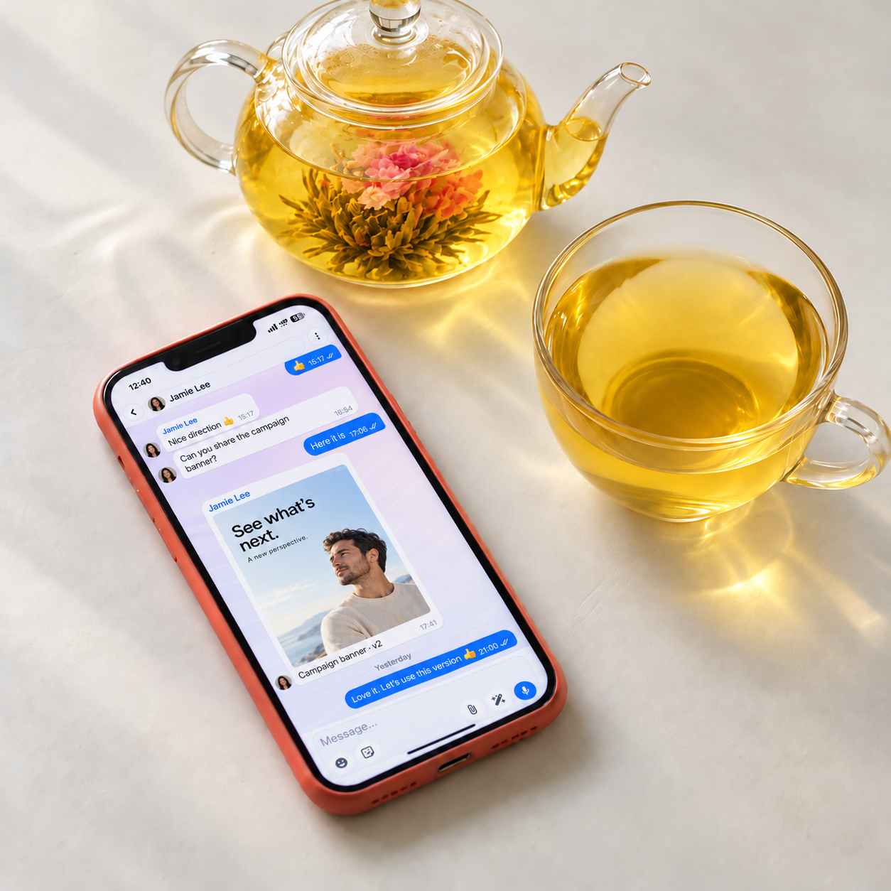 Чат Branzy на телефоне рядом со стеклянным чайником и чашкой чая